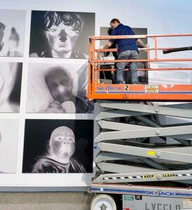 Darren Johnson installing Linda Alterwitz exhibition at Sahara West Library